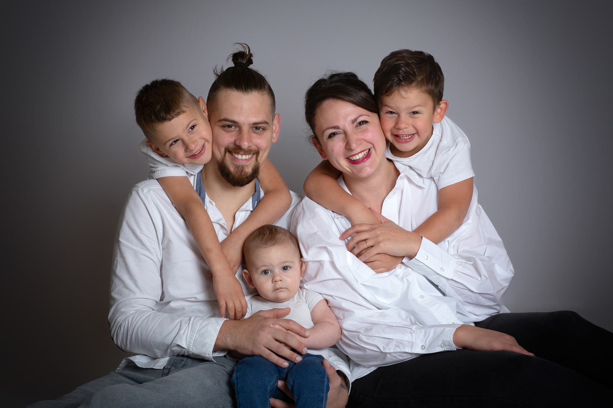 Portrait d’une famille en studio, capturant un moment complice et chaleureux