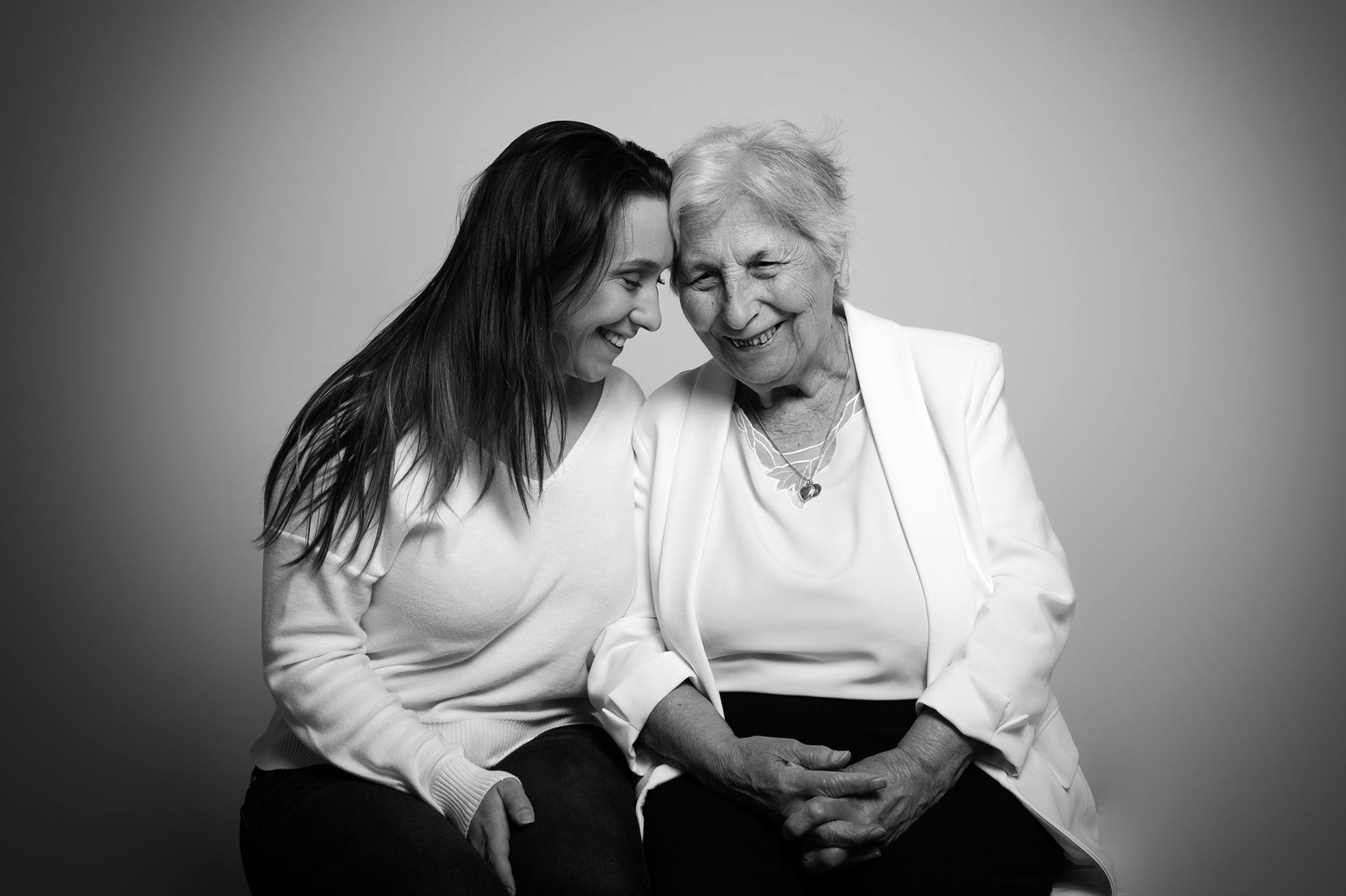 Photo d’une jeune femme souriante enlacée avec sa grand-mère, illustrant un moment de complicité et d’émotion familiale, prise par un photographe professionnel à Bressuire