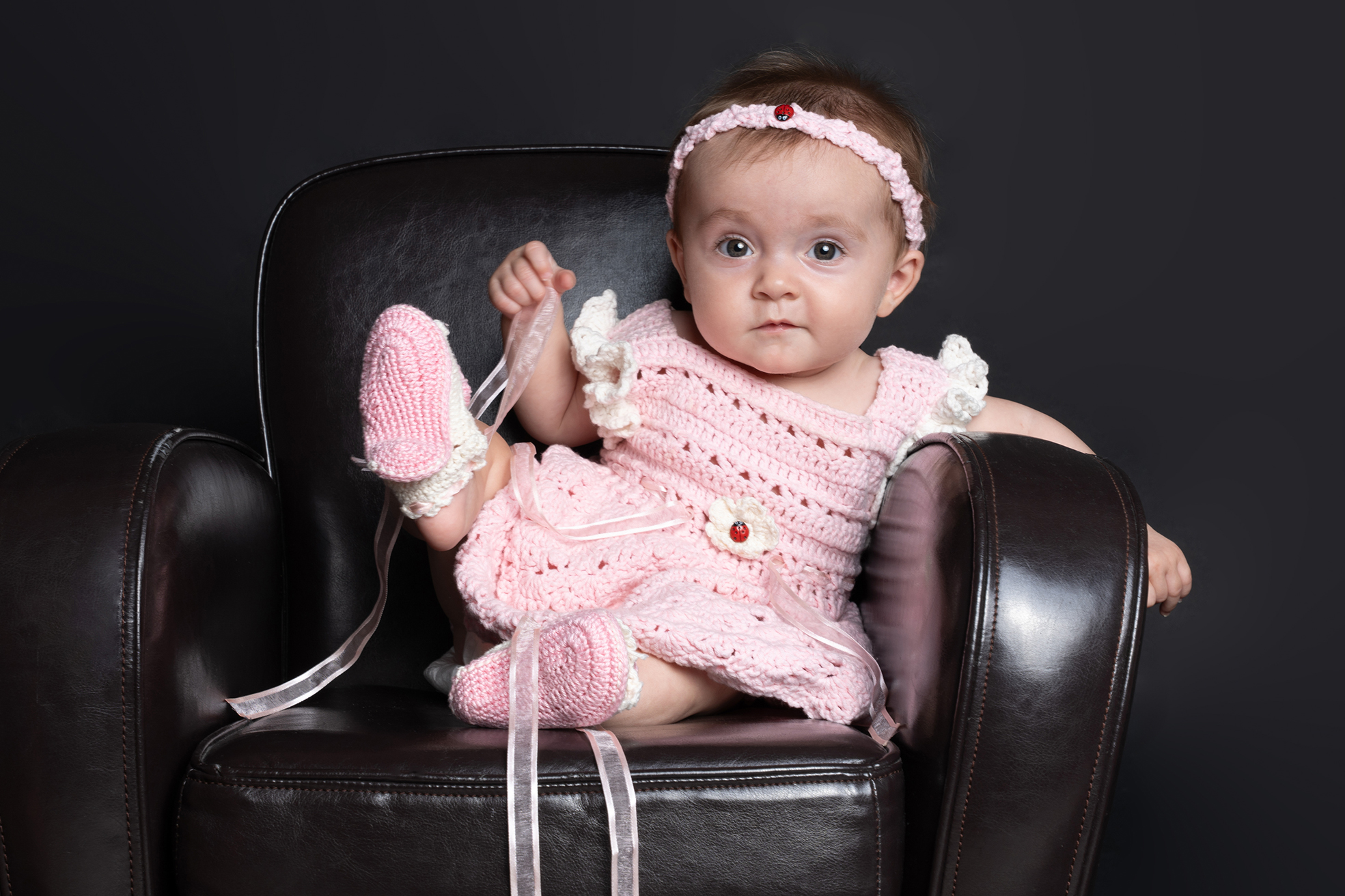 Photo d’une petite fille de six mois en studio, assise et souriante, prise par un photographe professionnel à Bressuire, illustrant un portrait bébé chaleureux et lumineux.