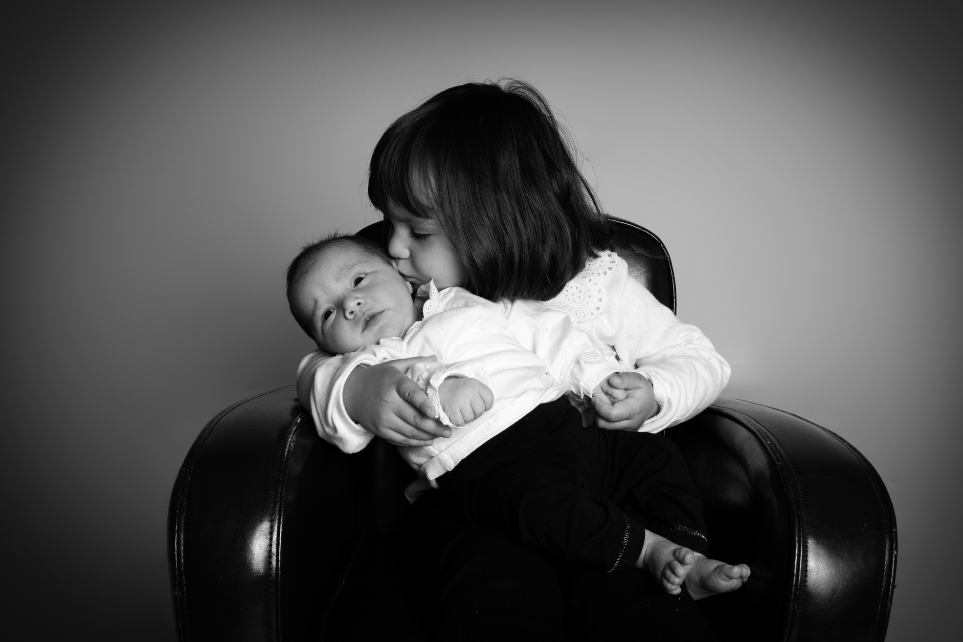 Aîné posant tendrement avec son nouveau-né lors d’une séance naissance en studio à Bressuire.