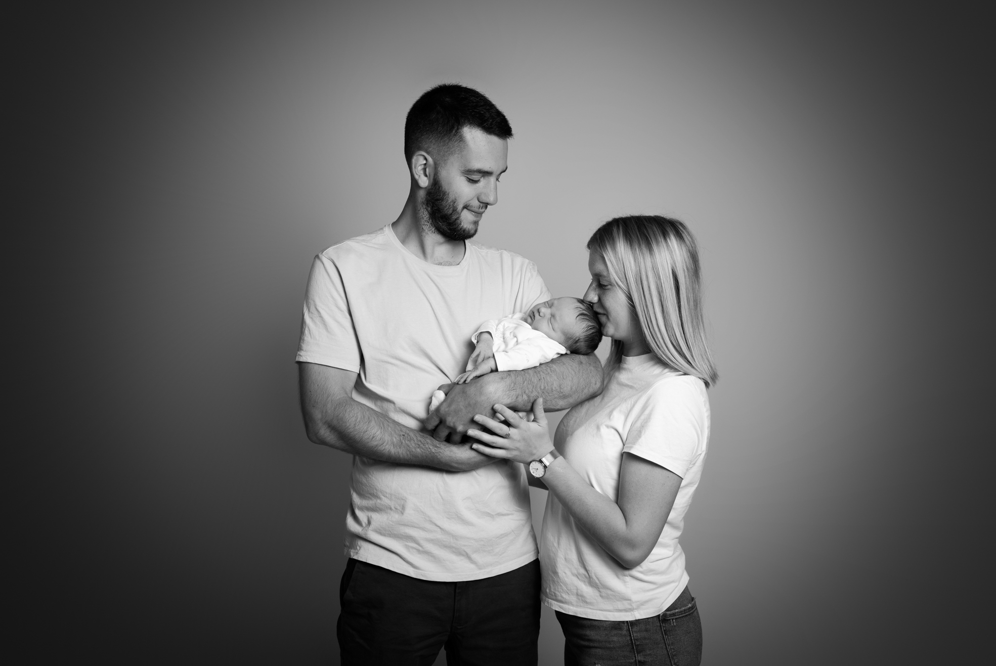 Nouveau-né tenu dans les bras des parents lors d’une séance naissance en studio.