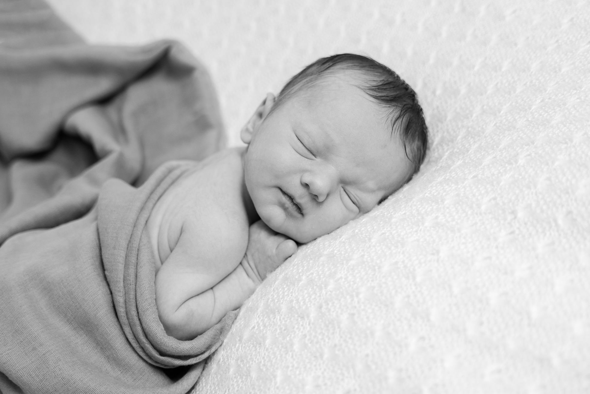 Nouveau-né posé sur le ventre, endormi, lors d’une séance photo en studio.