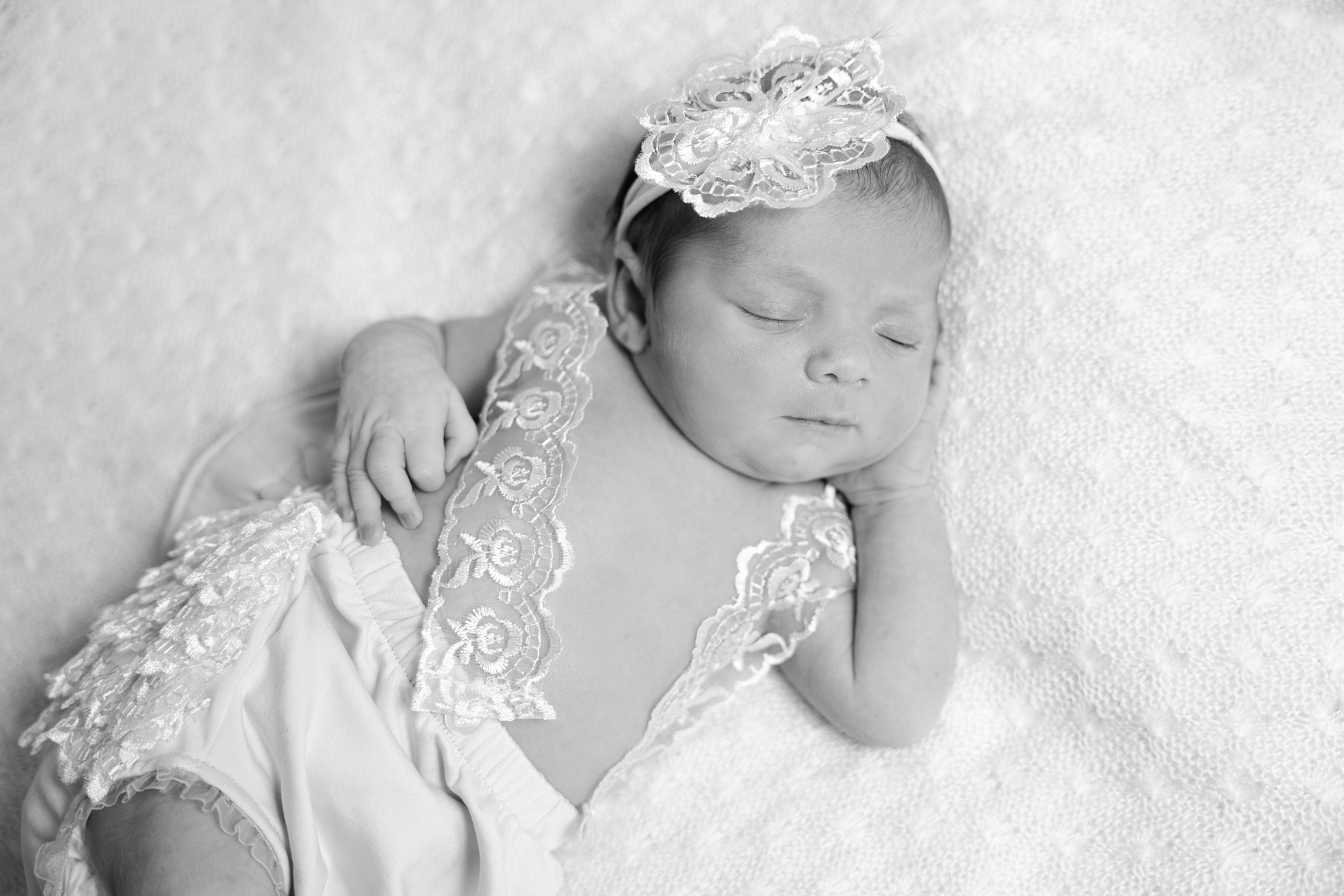 Nouveau-né allongé sur le ventre avec un bandeau décoratif en studio.