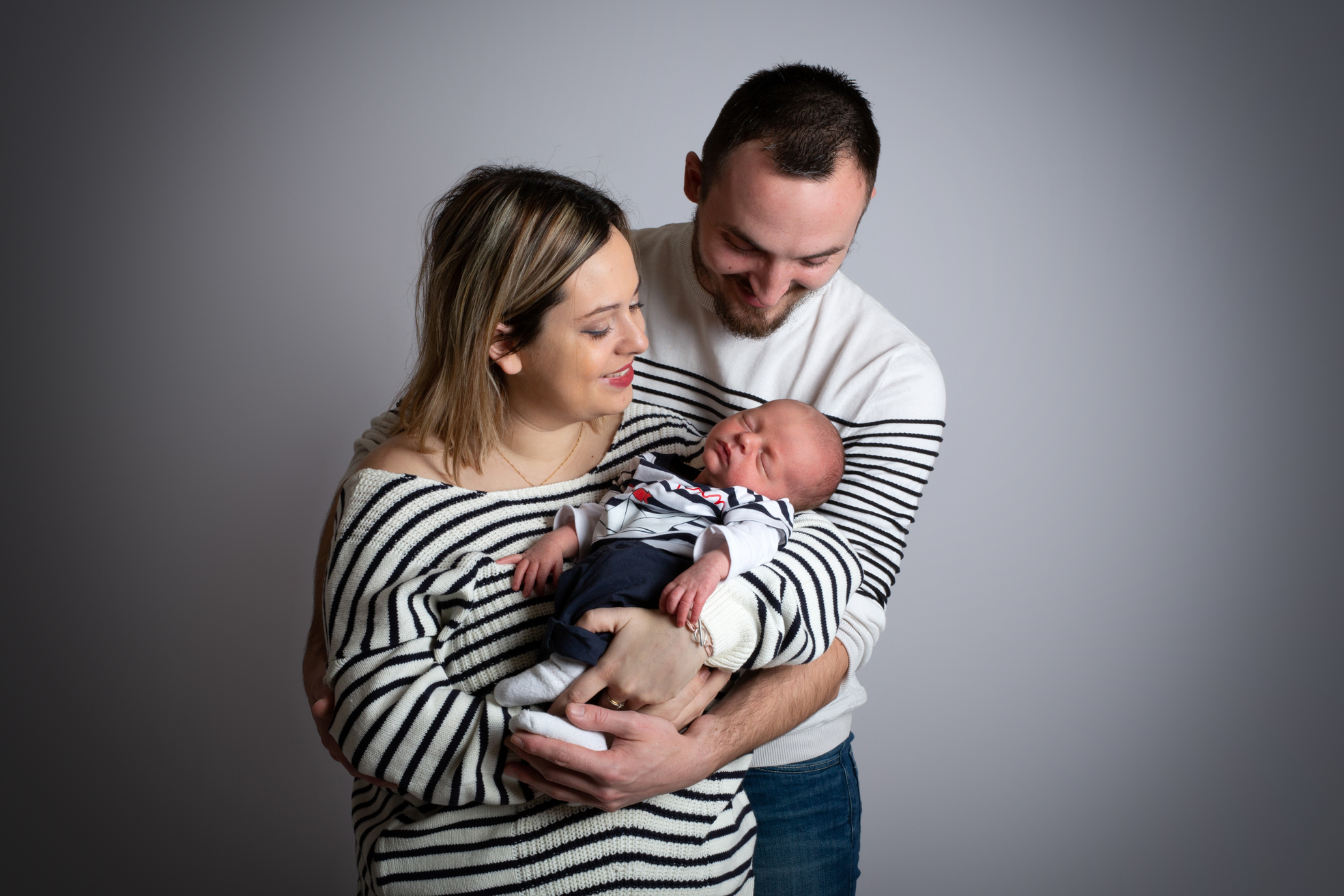 Parents embrassant leur nouveau-né lors d’une séance naissance en studio.