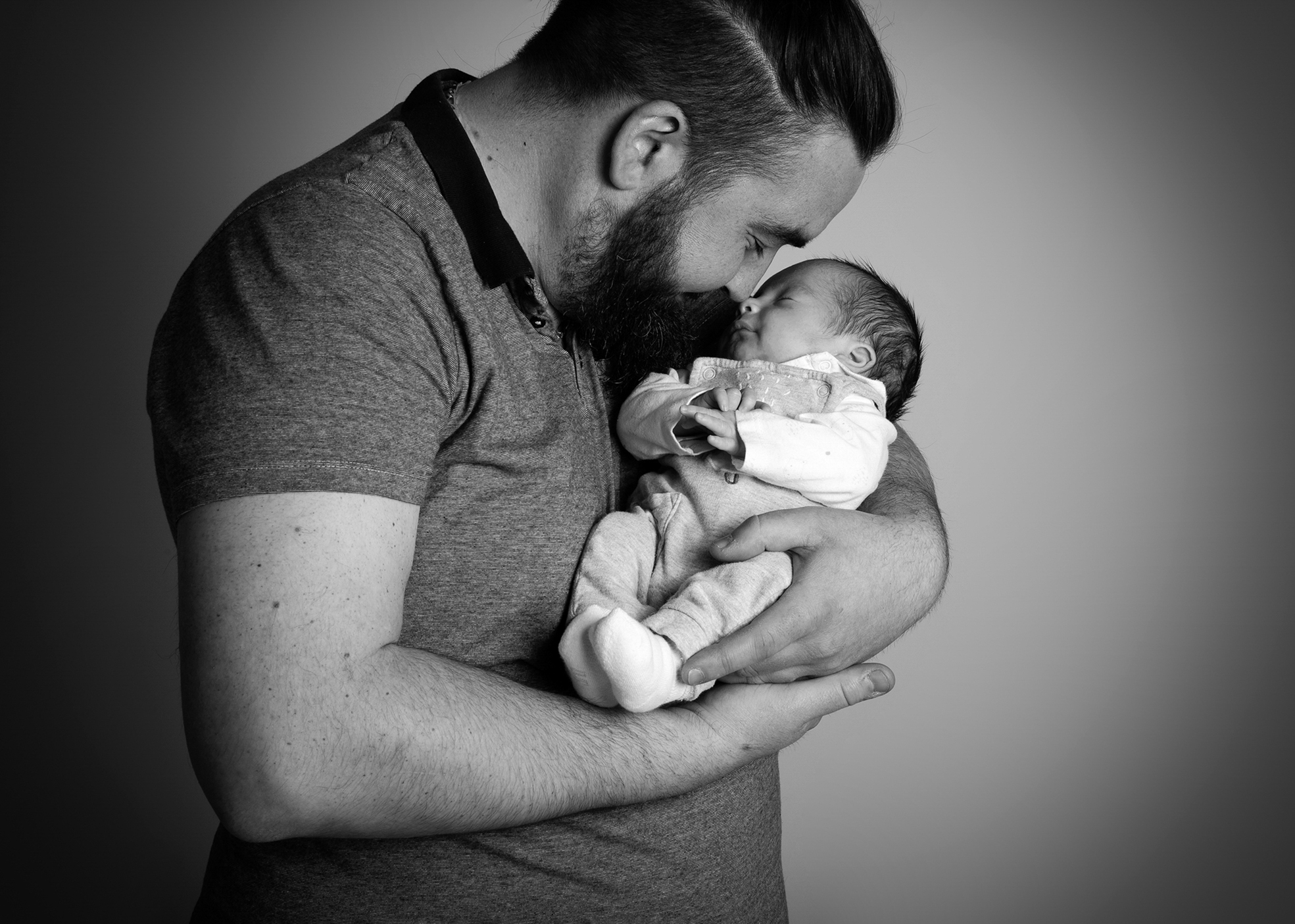 Nouveau-né recevant un bisou de son papa lors d’une séance photo en studio à Bressuire.