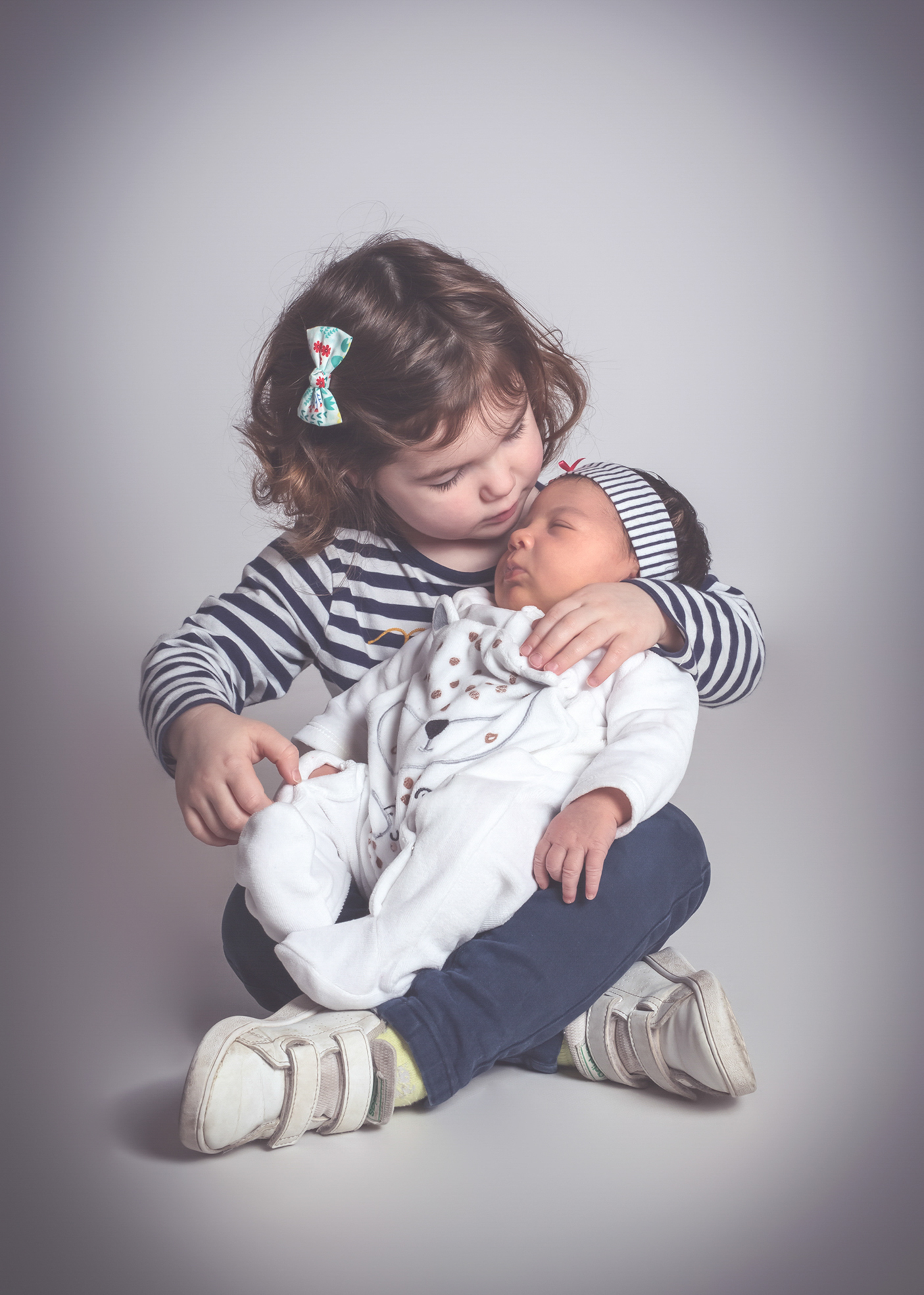 L’aîné embrassant son nouveau-né pendant une séance photo en studio à Bressuire.
