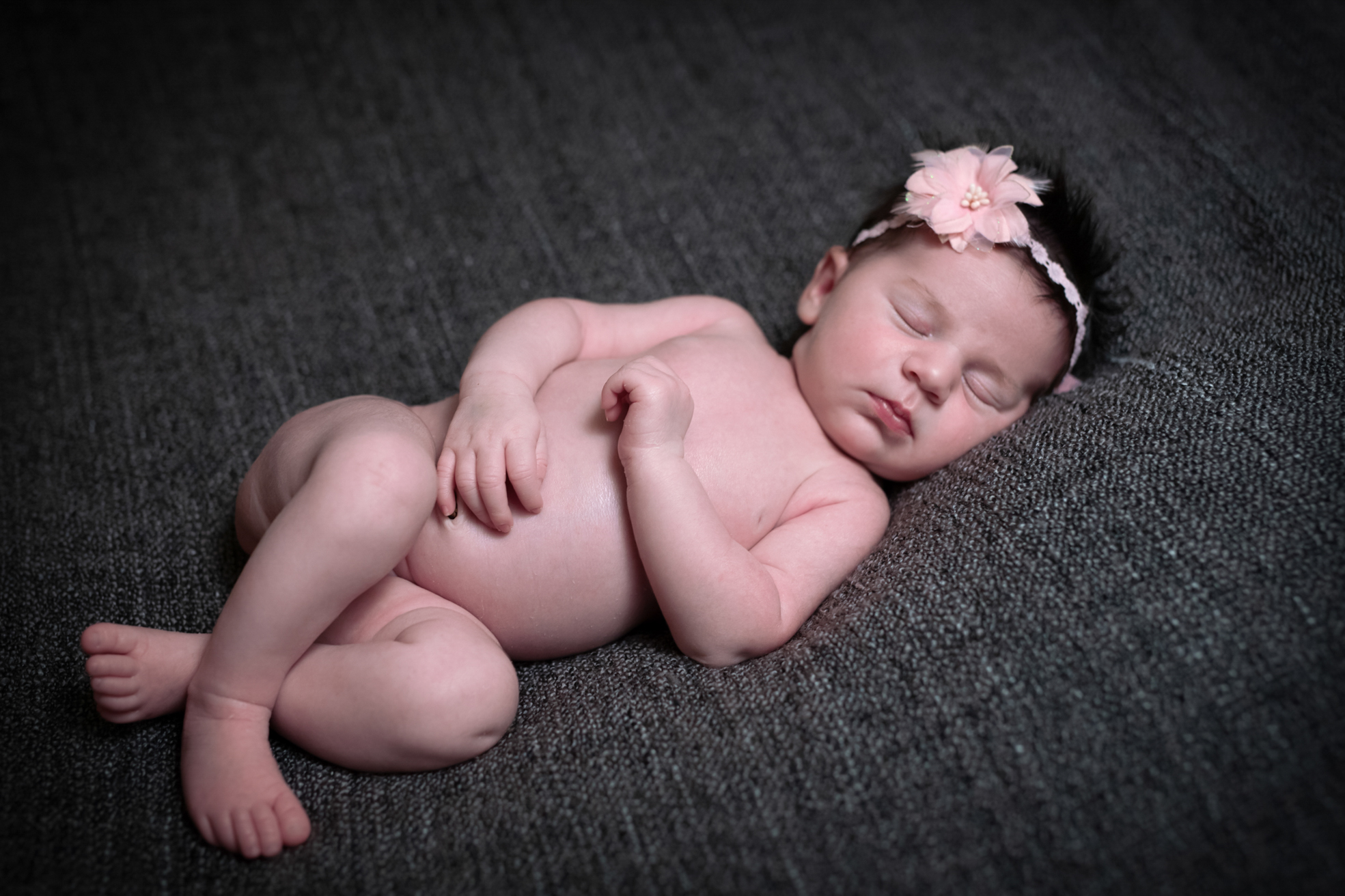 Nouveau-né allongé sur le dos, mains croisées sur le ventre en studio.