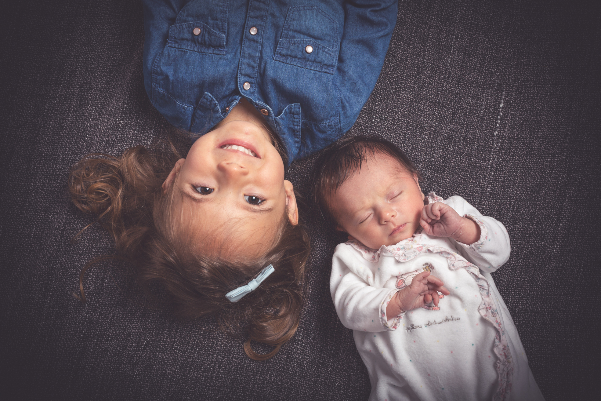 Fratrie posant ensemble avec le nouveau-né dans les bras de l’aîné en studio à Bressuire.