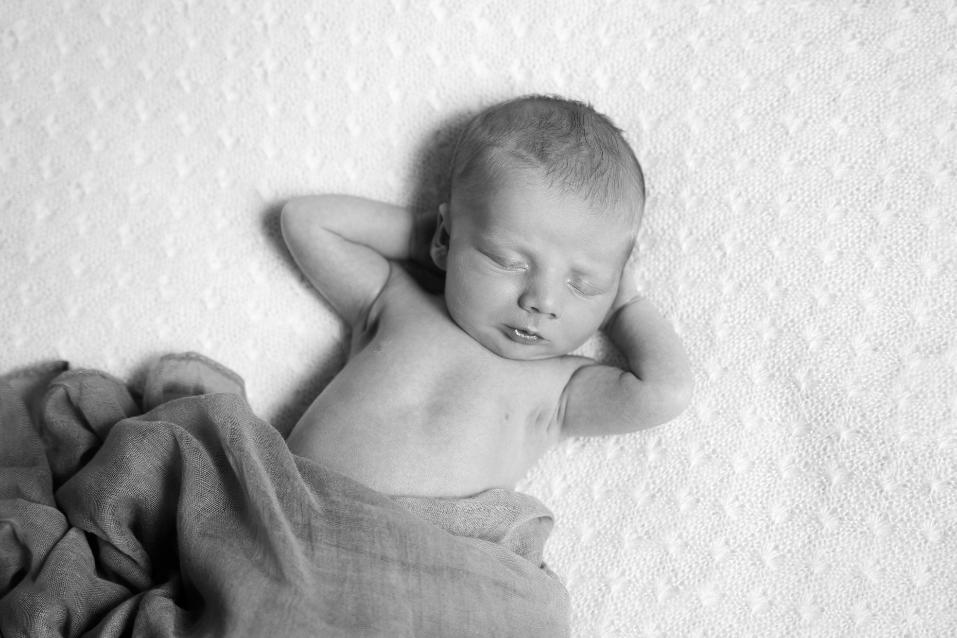 Nouveau-né endormi enveloppé dans un tissu moelleux sur un coussin.